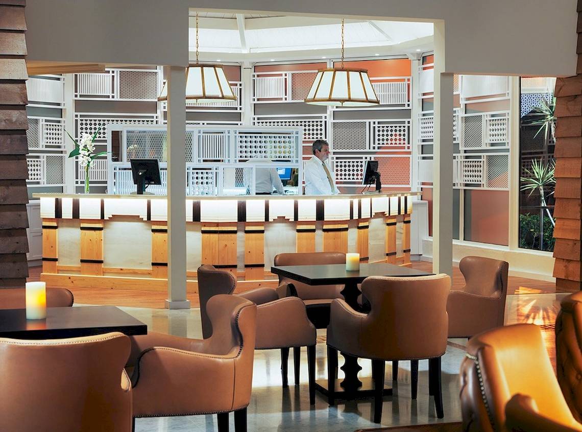 Innenansicht der Rezeption im H10 Playa Esmeralda Hotel mit Angestellten und Möbeln.