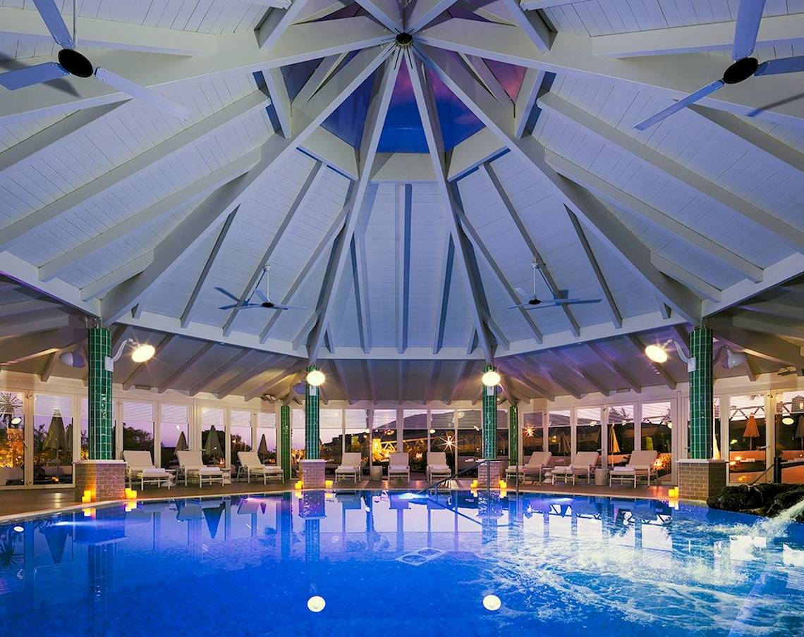 Innenpool im H10 Playa Esmeralda Hotel mit blauem Wasser und weißen Liegestühlen.