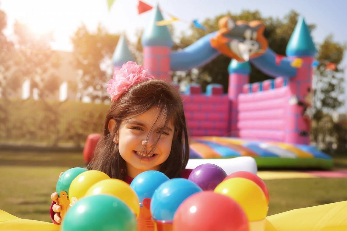 Ein junges Madchen lachelt und spielt mit bunten Ballons vor einem aufblasbaren Schloss