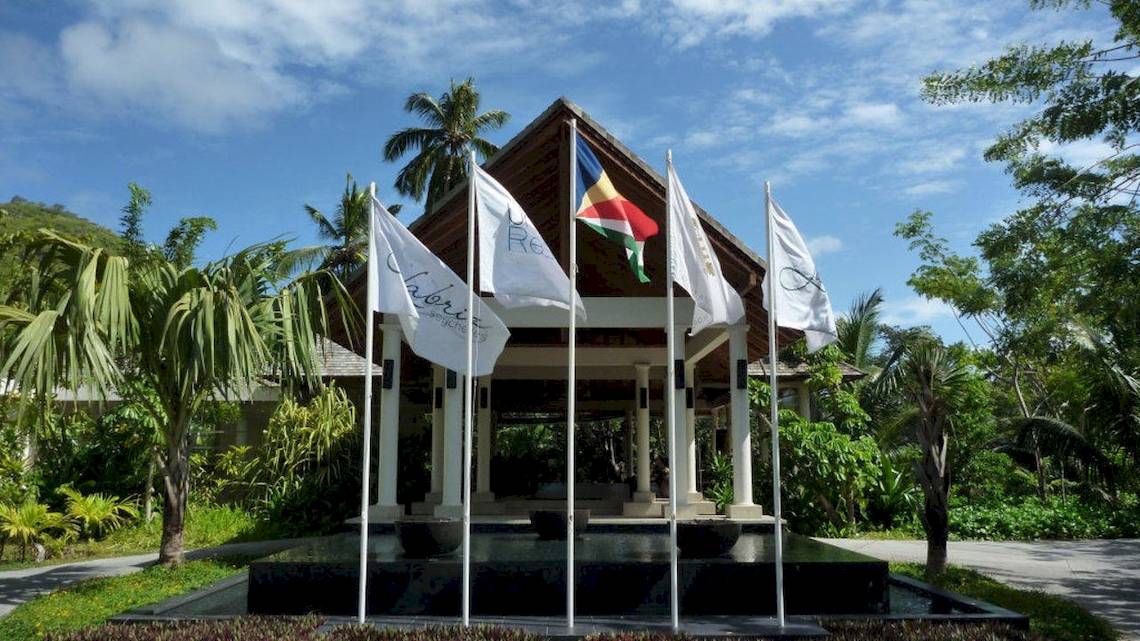 Eingang des Hilton Seychelles Labriz Resort & Spa mit mehreren Flaggen vor dem Gebäude.