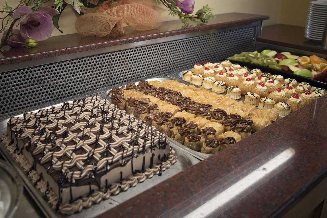 Verschiedene Kuchen und Desserts auf einer Theke im Eurovillage Achilleas Hotel.