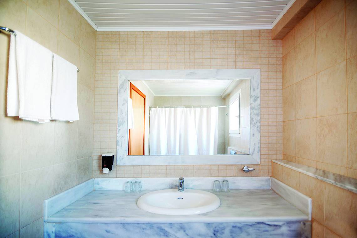 Ein Badezimmer mit einem Marmorwaschbecken, Spiegel und Handtüchern an der Wand.