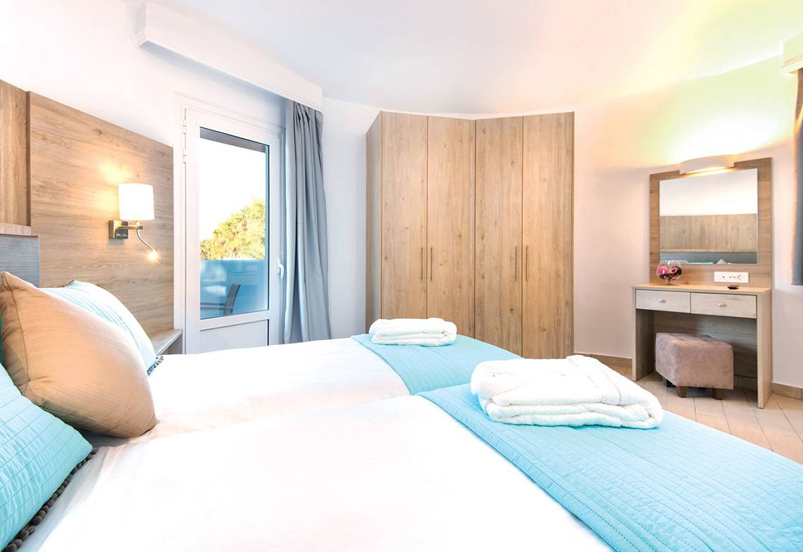 Zwei Betten mit blauen Decken und weißen Laken in einem Schlafzimmer im Eurovillage Achilleas Hotel.