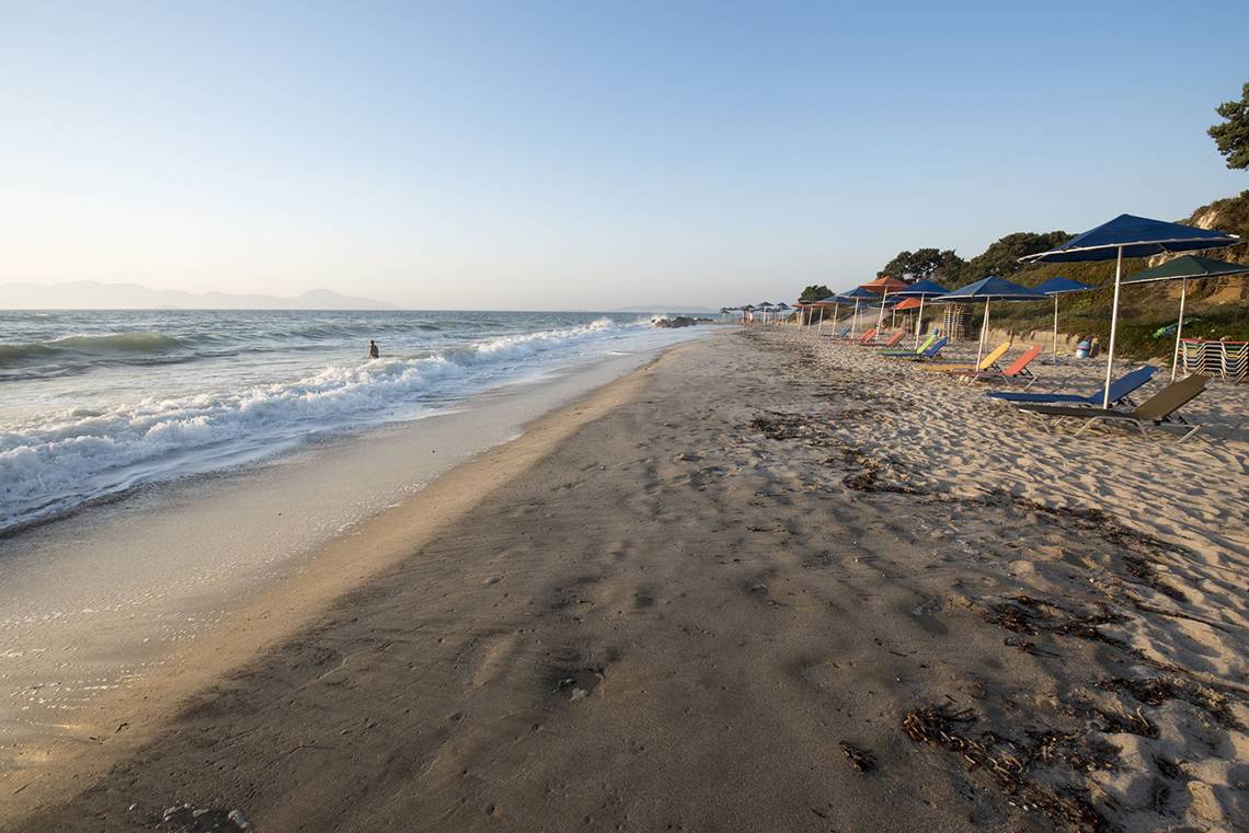 Strand mit Sonnenschirmen und Strandliegen am Meer bei Sonnenuntergang