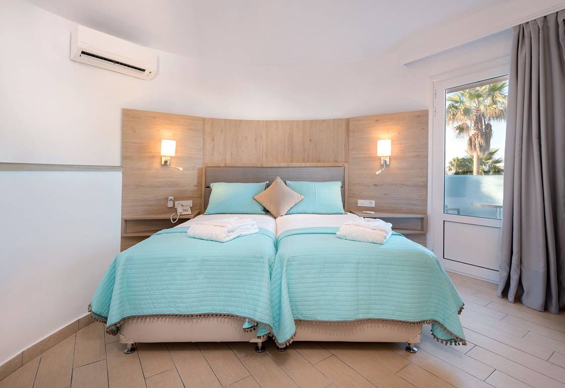 Doppelbett-Zimmer im Eurovillage Achilleas Hotel mit blauen Laken und Kissen.