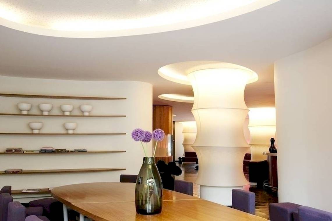 Ein eleganter Innenraum des Ku Damm 101 Hotels mit einem Tisch, auf dem eine Vase mit Blumen steht.