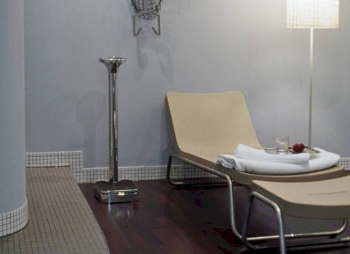 Relaxationsbereich im Hotel Ku Damm 101 mit Liege, Tisch und Leuchte.