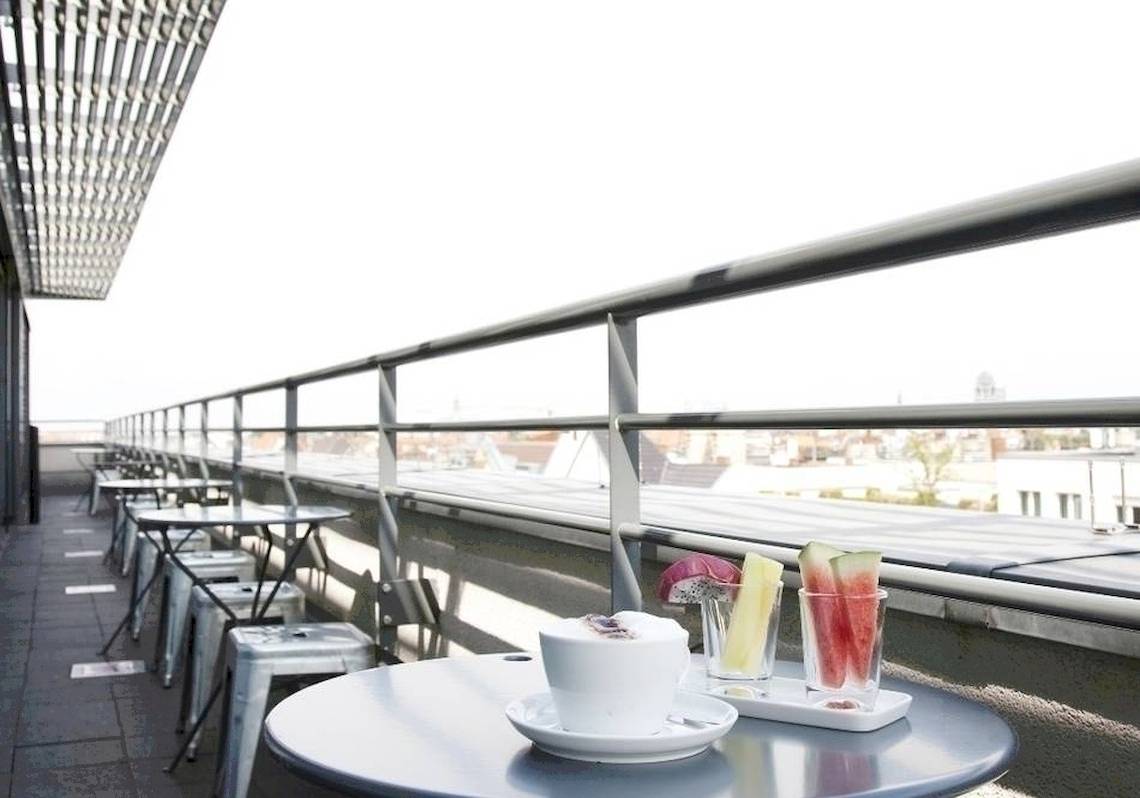 Dachterrasse des Ku Damm 101 Hotels mit Tischen, Stühlen und Getränken