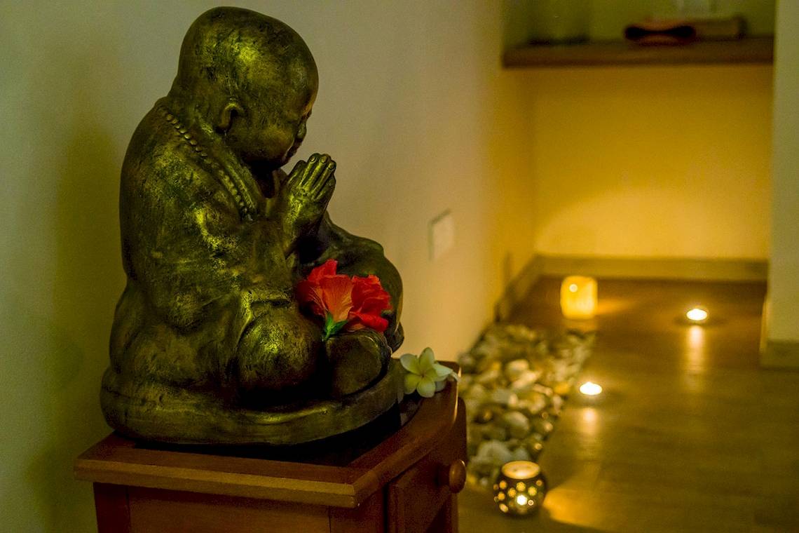 Buddha-Statue im Le Peninsula Bay Beach Resort & Spa mit roten und weißen Blumen.