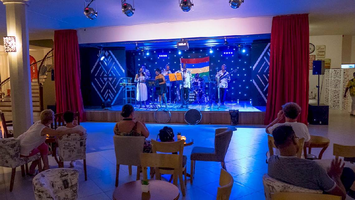 Le Peninsula Bay Beach Resort & Spa mit einer Band, die auf der Bühne auftritt, während Gäste zuschauen.