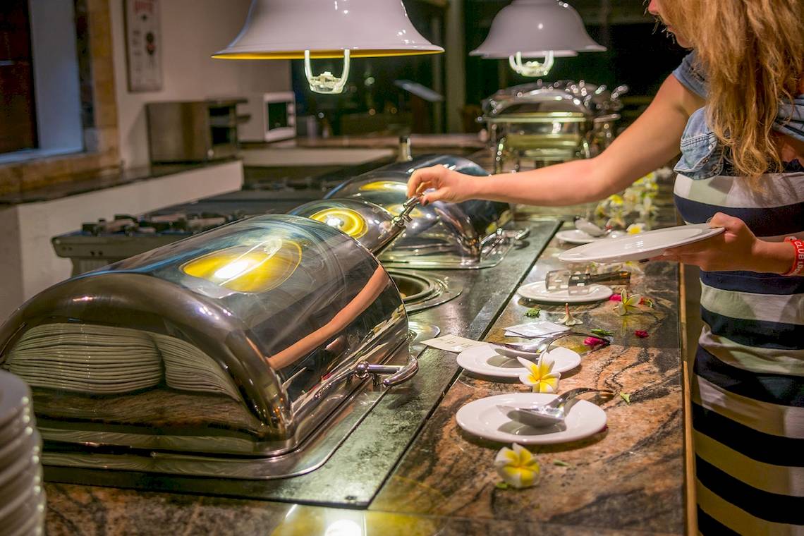 Frau bedient sich am Buffet im Le Peninsula Bay Beach Resort & Spa.