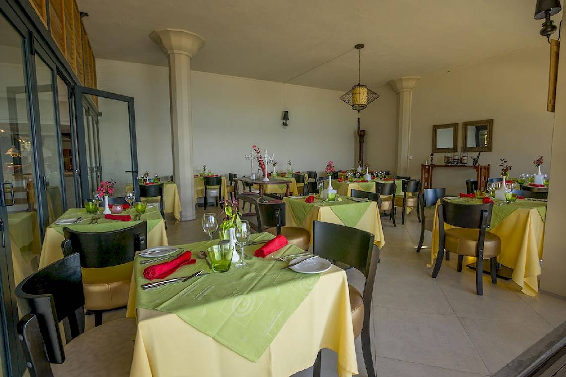 Restaurant im Le Peninsula Bay Beach Resort & Spa mit gedeckten Tischen und Stühlen.
