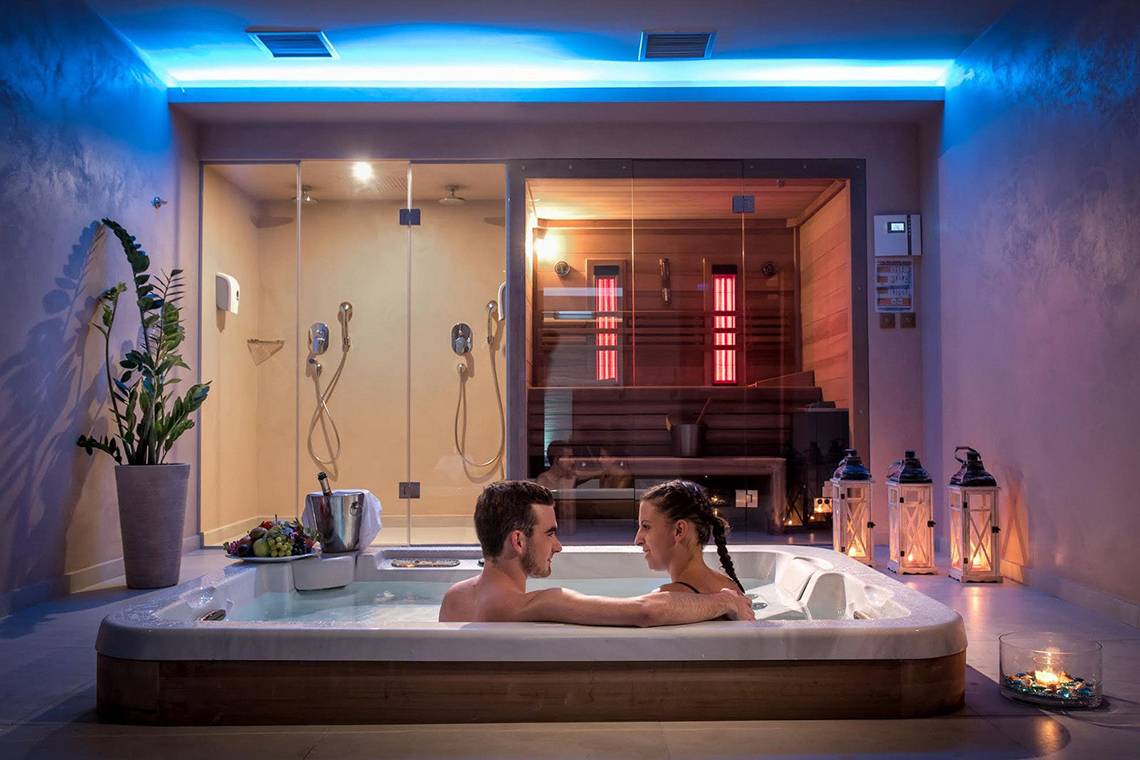 Paar im Whirlpool im Corissia Princess Hotel mit beleuchteten Wänden und einer Sauna im Hintergrund