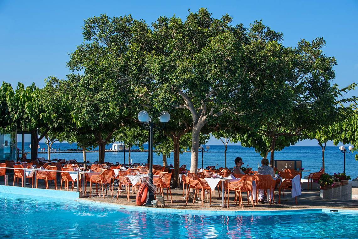 Sitzgelegenheiten im Freien am Pool des Corissia Princess Hotels, mit Blick auf das Meer.