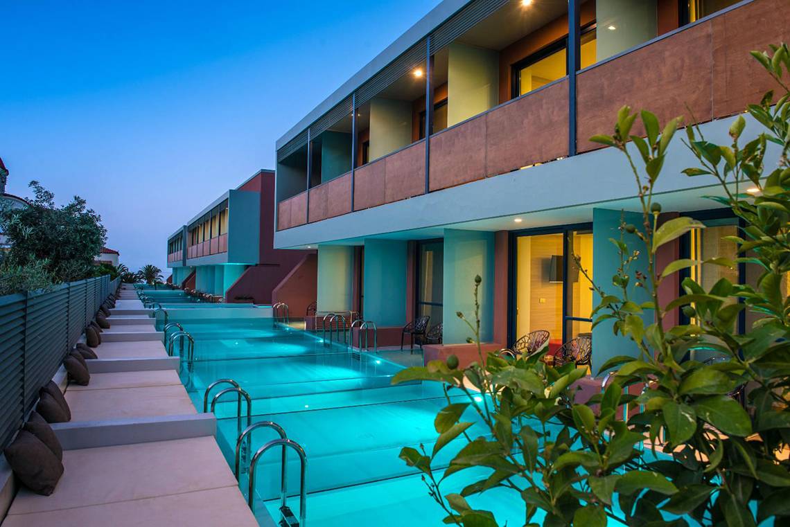 Corissia Princess Hotel Pool bei Nacht mit blauem Licht und Liegestühlen.