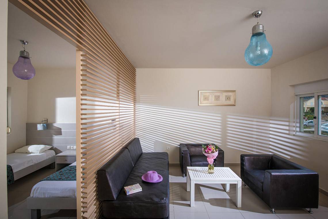 Inneneinrichtung eines Schlafzimmers im Corissia Princess Hotel mit zwei Betten, Sofas, Tisch und Blumen.