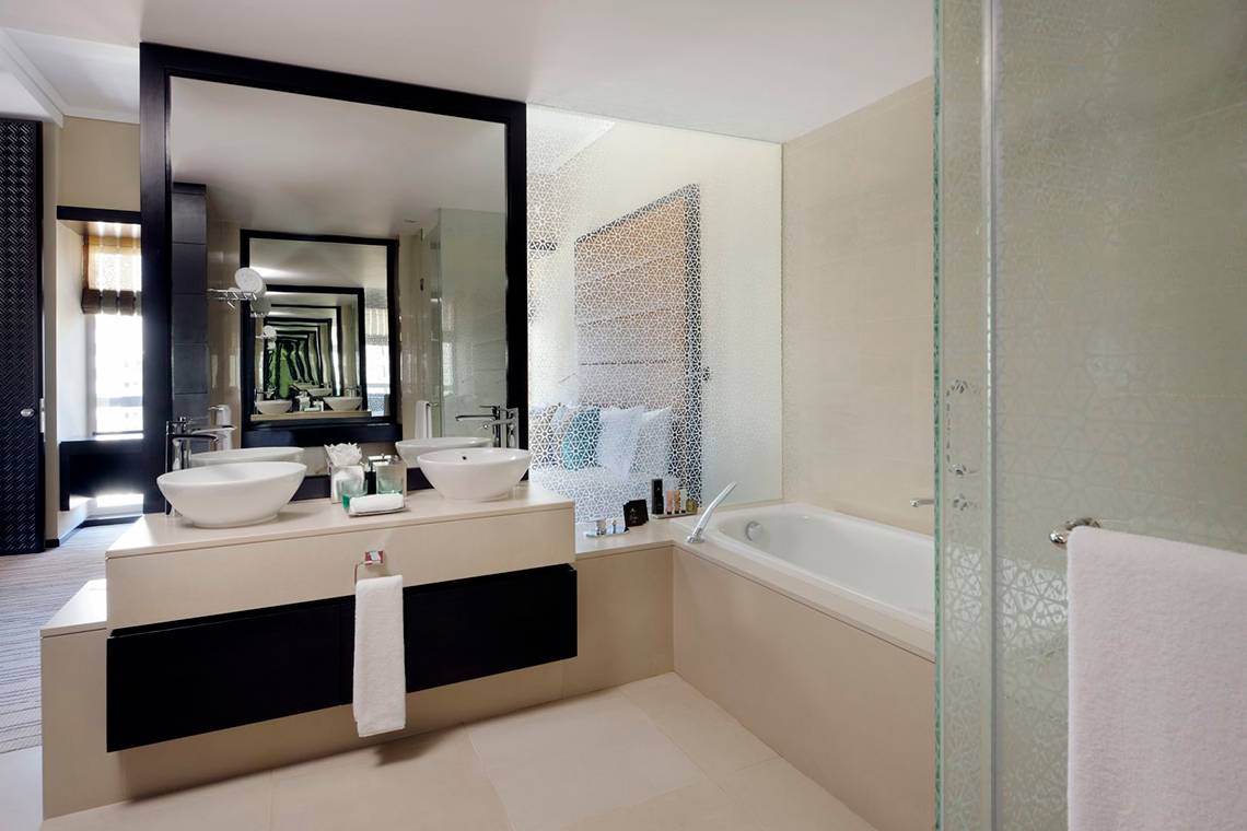 Badezimmer im Southern Sun Abu Dhabi Hotel mit zwei Waschbecken und Badewanne.