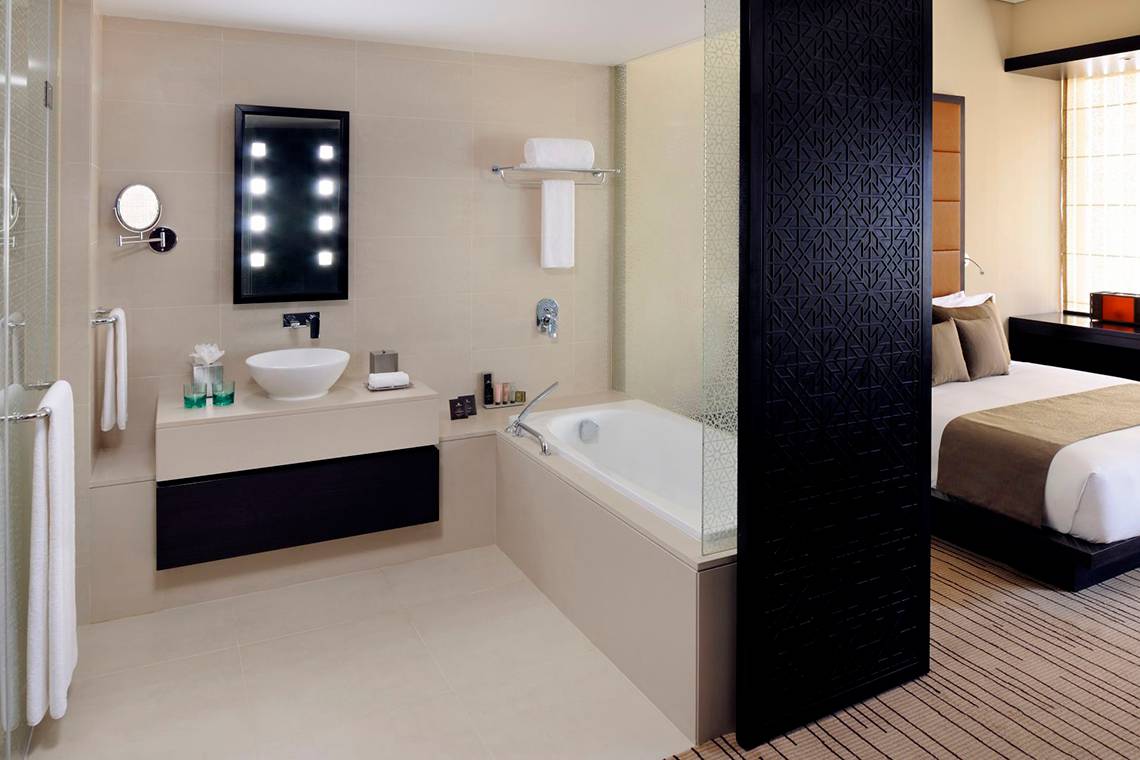 Hotelzimmer mit Badezimmer und Bett im Southern Sun Abu Dhabi