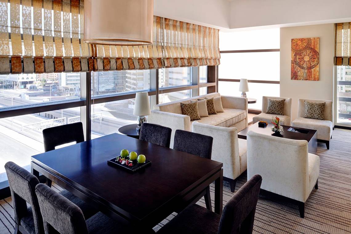 Innenansicht einer Suite im Southern Sun Abu Dhabi Hotel mit Möbeln und Blick auf die Stadt.