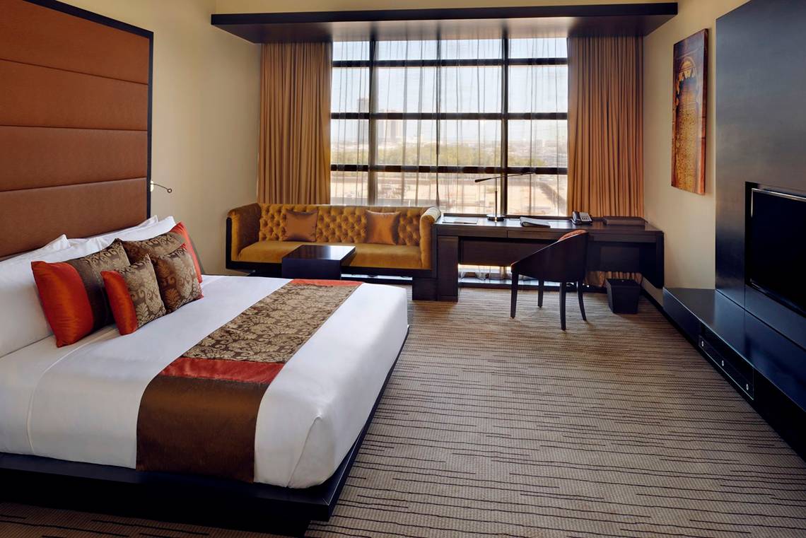 Hotelzimmer im Southern Sun Abu Dhabi mit Bett, Schreibtisch und Aussichtsfenster.
