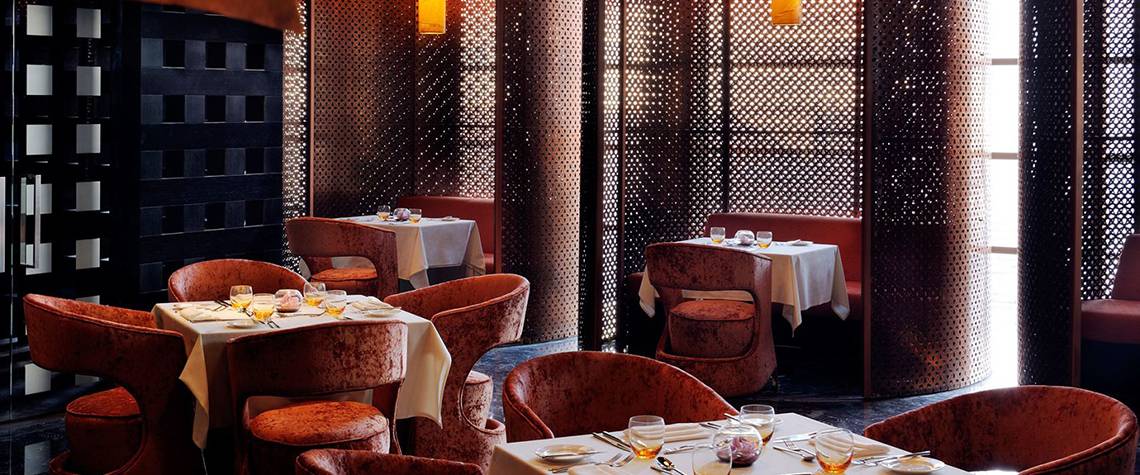 Innenansicht des Restaurants im Southern Sun Abu Dhabi mit braunen Stühlen und Tischen.