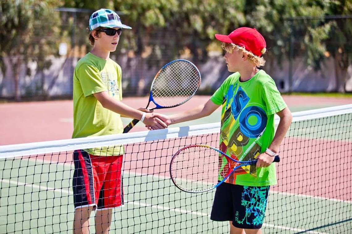 Zwei junge Spieler auf einem Tennisplatz schütteln sich die Hände.