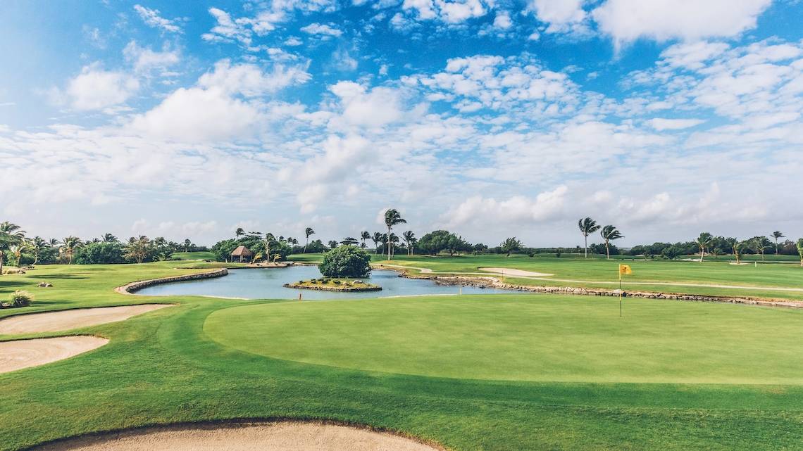 Golfplatz beim Iberostar Selection Cancun Hotel mit Wasserhindernis und Palmen
