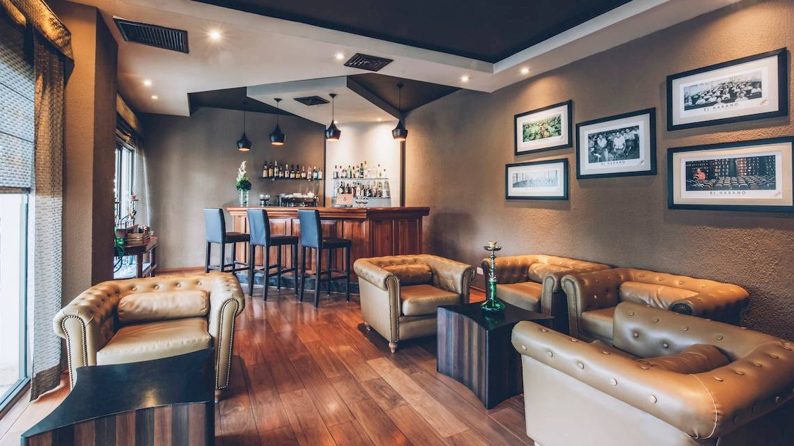 Hotellounge im Iberostar Selection Cancun mit Bar, Sesseln und Bildern an der Wand.