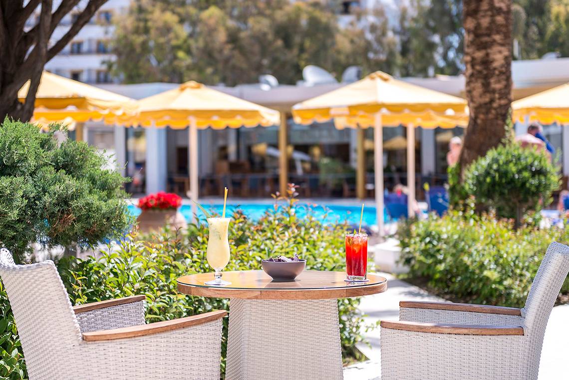 Ein Tisch im Freien mit zwei Cocktails und einem Hotel im Hintergrund.