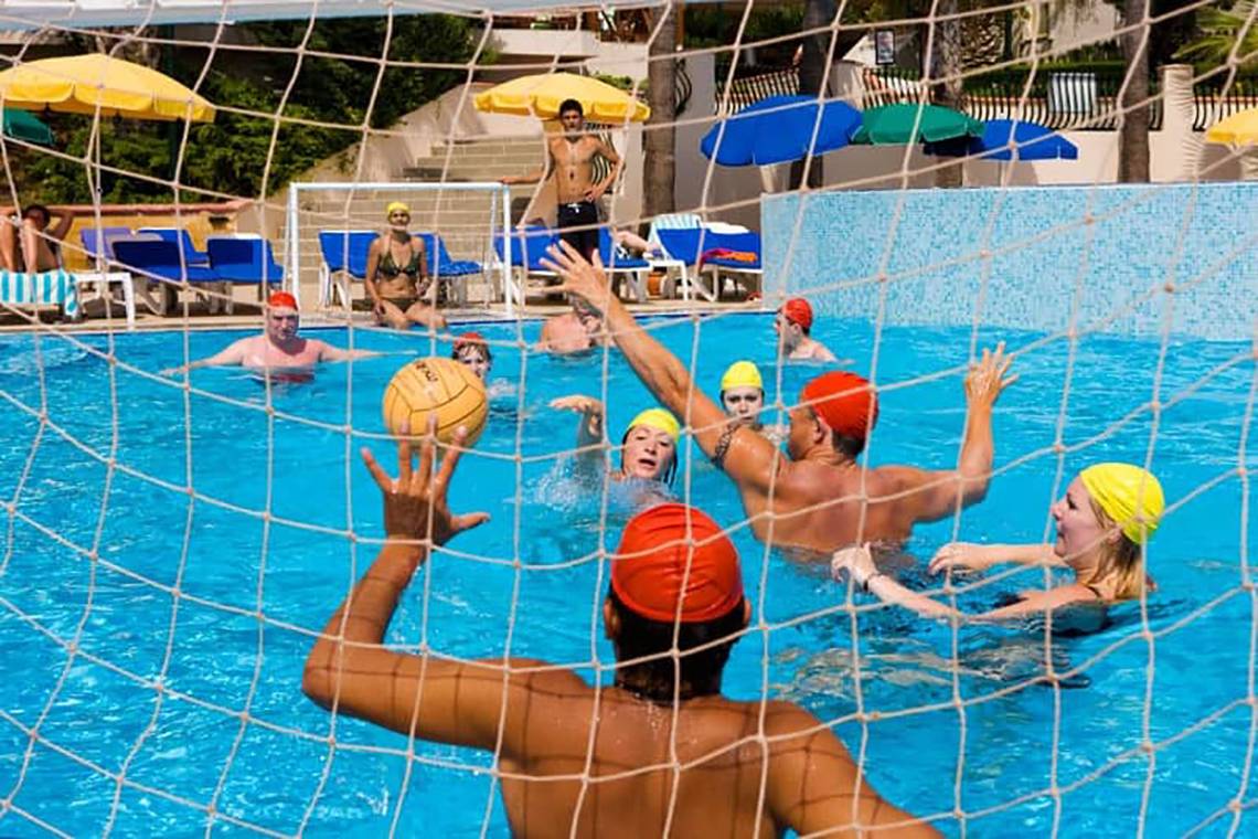 Gruppe von Männern und Frauen spielt Wasserball im Pool des Fantasia Hotel De Luxe