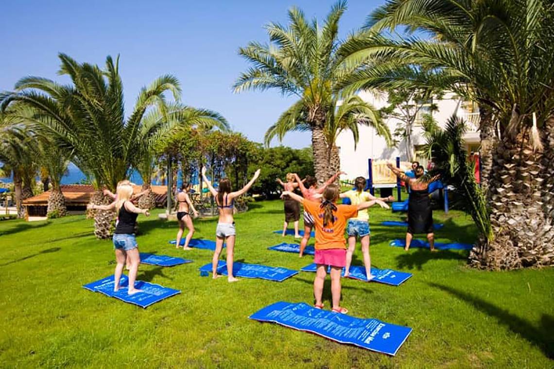 Yoga-Kurs im Freien im Fantasia Hotel De Luxe mit mehreren Teilnehmern auf Matten.