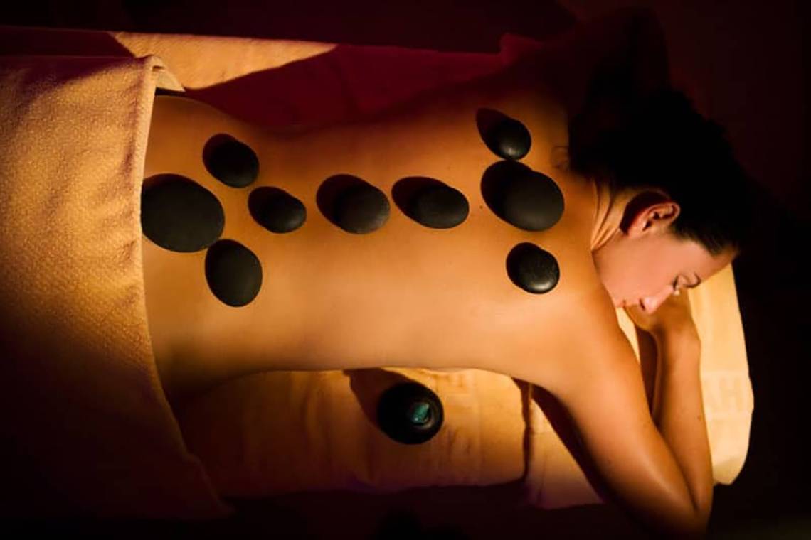 Frau genießt eine heiße Steinmassage im Hotel Fantasia De Luxe