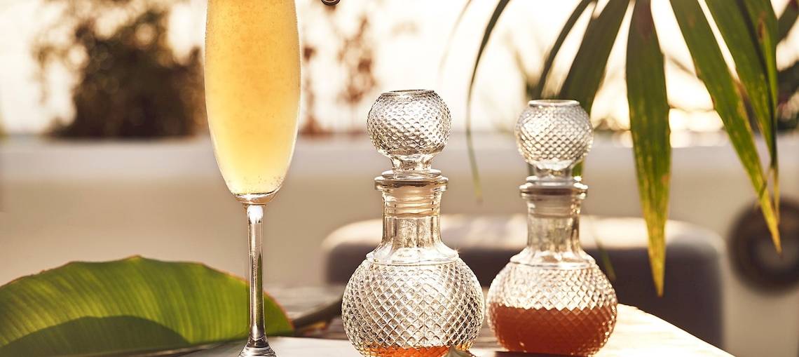 Ein Glas Champagner und zwei Karaffen mit Honig auf einem Tisch mit Palmenblatt