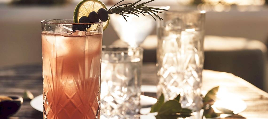 Cocktail im Glas mit Rosmarin und Limette auf einem Tisch