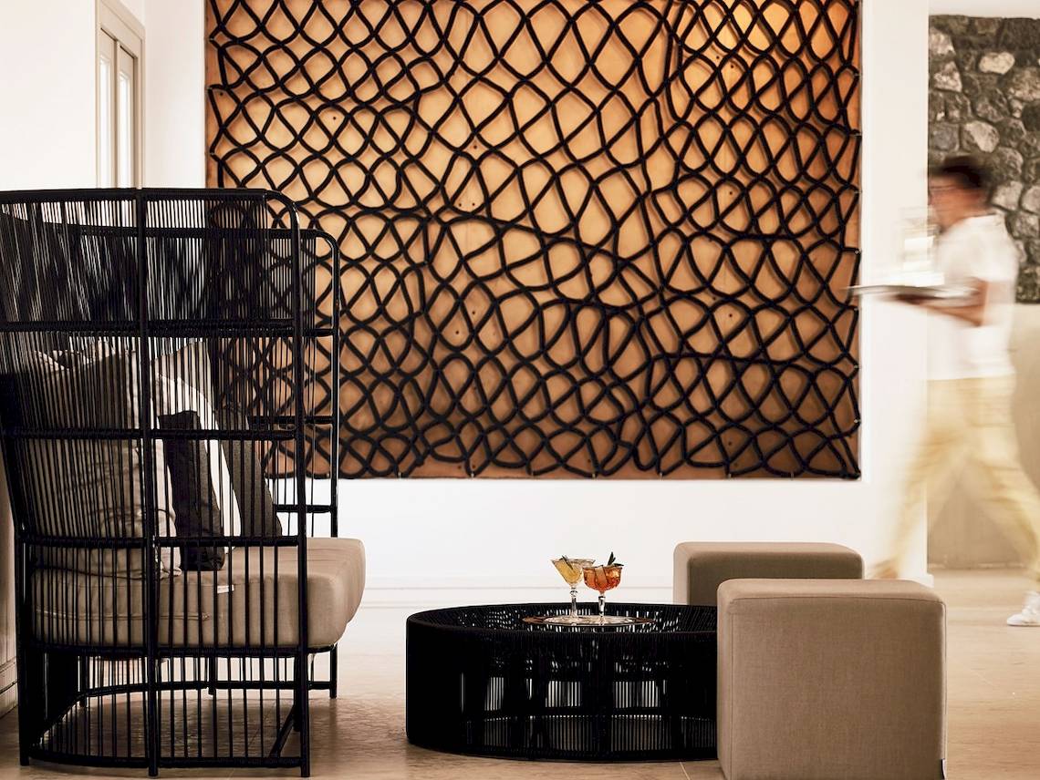 Loungebereich im Santo Pure Oia Suites & Villas mit modernem Möbeldesign und Hintergrundmuster.