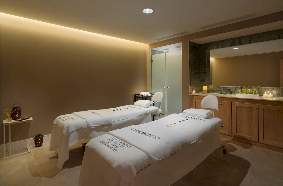 Behandlungsraum im H10 Atlantic Sunset Spa mit zwei Massageliegen und einem Spiegel.