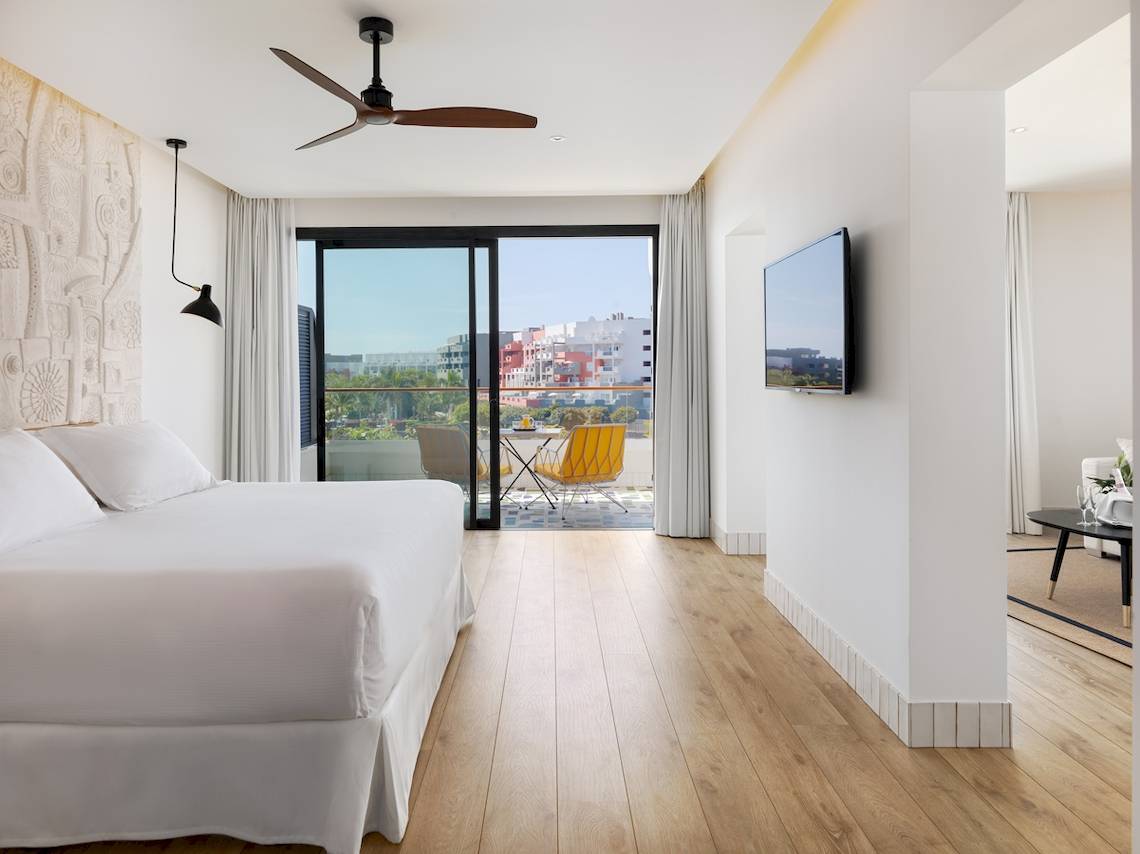 Innenansicht eines Zimmers im H10 Atlantic Sunset Hotel mit Bett, Tisch, Stühlen und Terrassenblick.