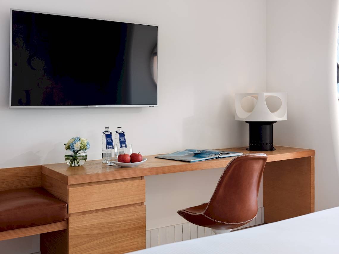 Arbeitsbereich des Zimmers im H10 Atlantic Sunset Hotel mit Fernseher, Schreibtisch, Apfel und Lampe.