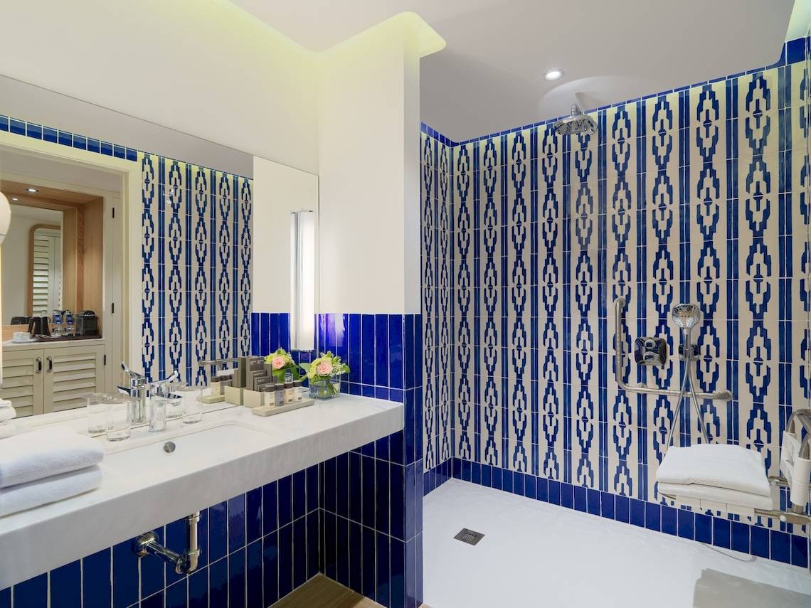 Badezimmer im H10 Atlantic Sunset Hotel mit blauen und weißen Kacheln und einer Dusche