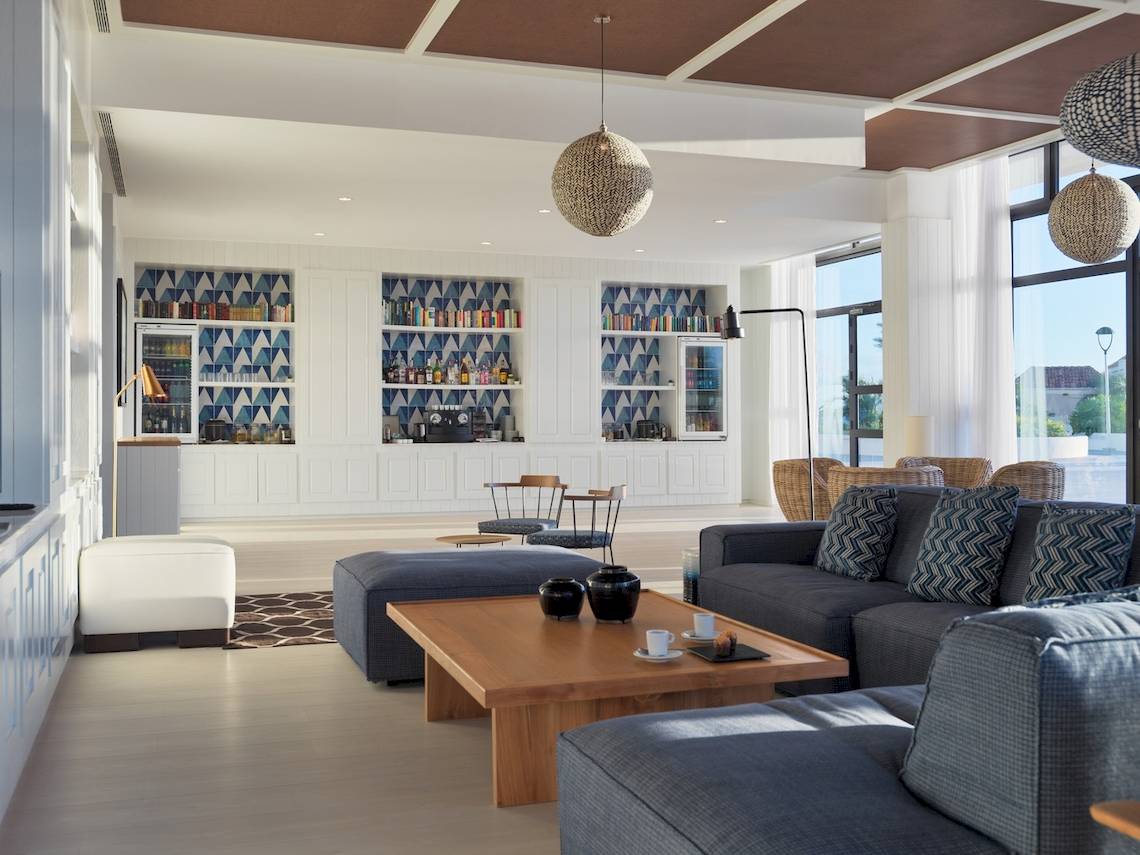 Innenbereich des H10 Atlantic Sunset Hotels mit Loungebereich, Sofas, Couchtisch und Bücherregalen.