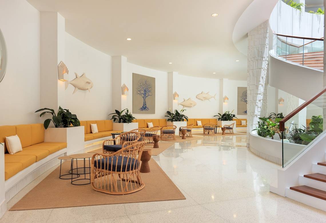 Lobby des H10 Atlantic Sunset Hotels mit gelben Sofas, runden Stühlen und Pflanzen.