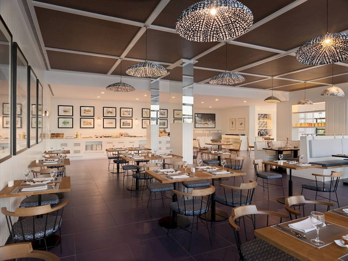Innenansicht des Restaurants des H10 Atlantic Sunset Hotels mit Tisch und Stühlen, Tischdecken, Weinläsern und dekorativen Bildern an der Wand.