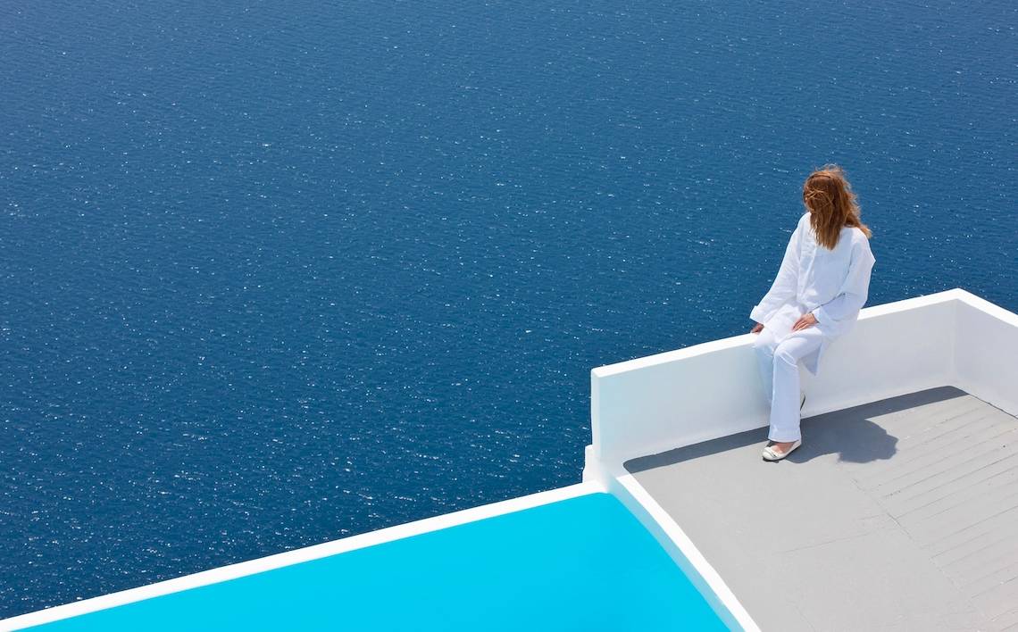 Frau auf der Terrasse von Katikies Chromata Santorini mit Blick auf das Meer