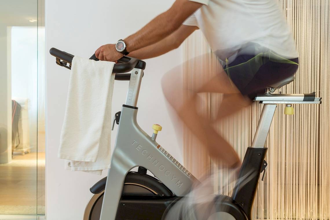 Mann trainiert auf einem Technogym-Fahrrad im Katikies Chromata Santorini Hotel