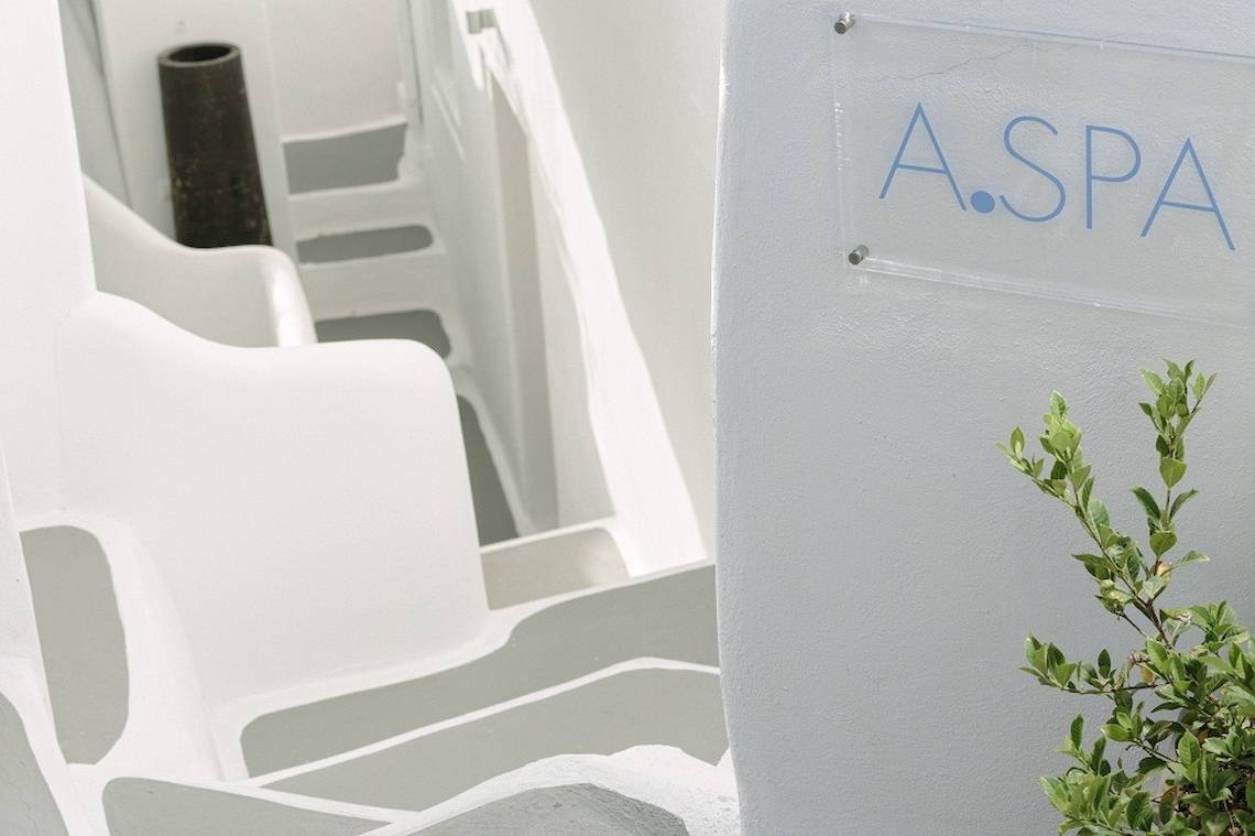 Eingang zum A.SPA im Katikies Chromata Hotel auf Santorini mit weißen Stufen und einer Pflanze.