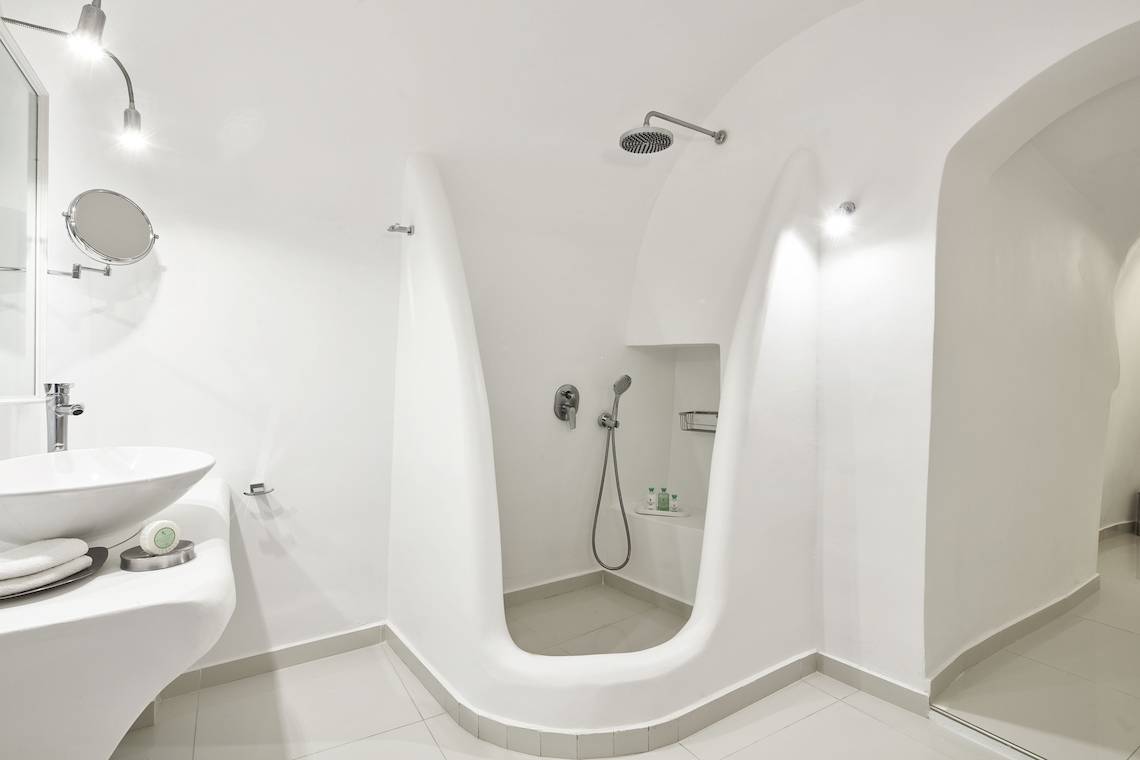 Ein Badezimmer im Katikies Chromata Santorini Hotel mit weißen Wänden und Boden.