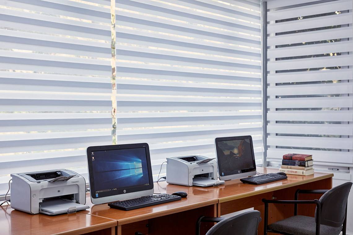 Arbeitsplatz im Grecian Bay Hotel mit Computern, Druckern, Tastaturen, Mäusen und Büchern