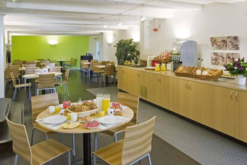 Frühstücksraum des Nova Hotels mit Tischen, Stühlen und Frühstücksbuffet.