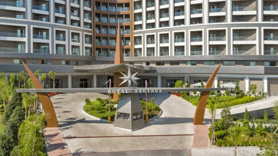 Außenansicht des Royal Seginus Hotels mit gepflegtem Eingangsbereich und hohem Gebäude.