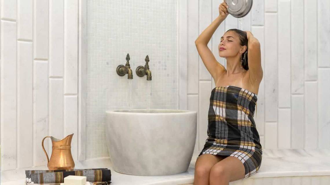 Eine Frau genießt eine Dusche im Royal Seginus Hotel.